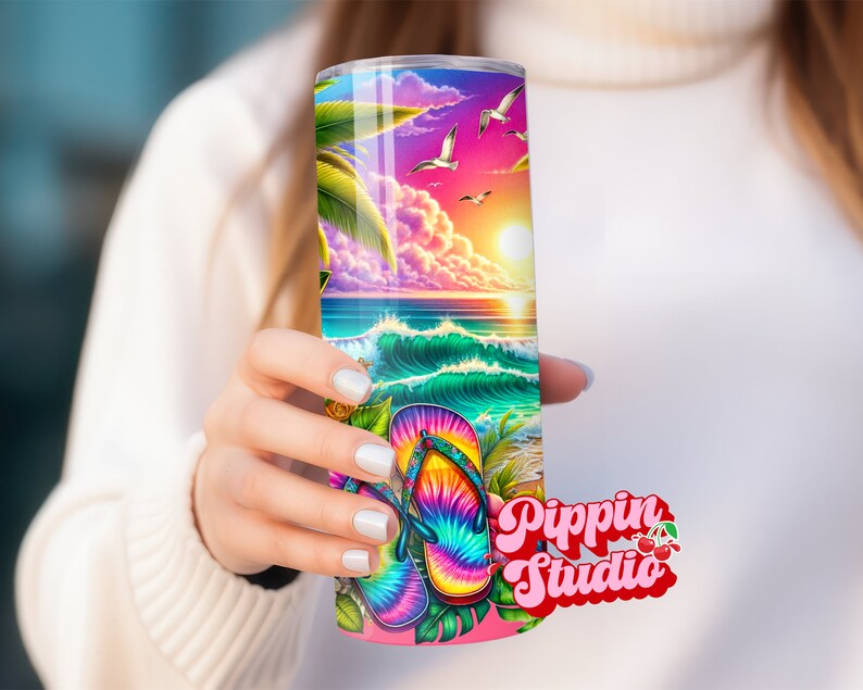 May include: A colorful stainless steel tumbler with a beach scene and tie-dye flip flops. The tumbler has a pink lid and a white background with the text "Pippin Studio" in pink and red.