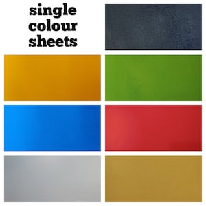 Könnte beinhalten: Sechs einfarbige Papierbögen in Schwarz, Gelb, Grün, Blau, Silber und Gold.
