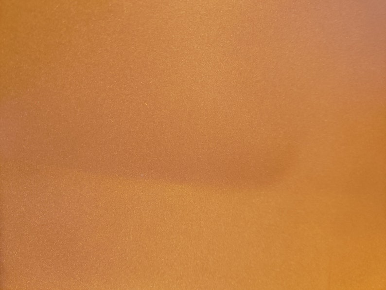 May include: A close-up of a smooth, textured, metallic gold surface.
