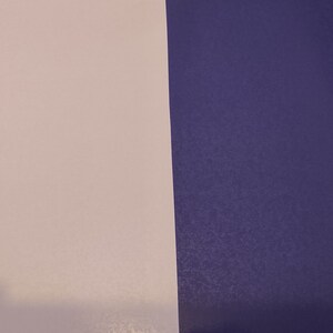 May include: A close-up of a vertical split background. The left side is a light pink color and the right side is a dark purple color.