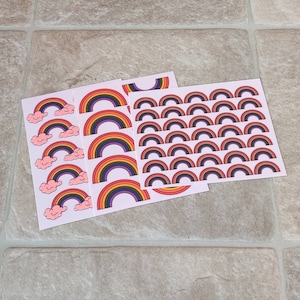 May include: Three sheets of rainbow stickers with different sizes and designs. The largest sheet has 36 small rainbow stickers. The other two sheets have larger rainbow stickers with clouds.
