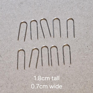 Könnte beinhalten: Zwölf silberne U-förmige Haken aus Metall, 1,8 cm hoch und 0,7 cm breit.