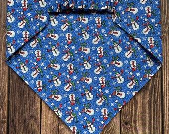 May include: Blue bandana with a white and red snowman pattern. The bandana has a ruffled edge and is made of cotton fabric.