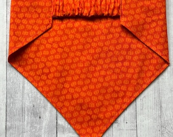 Peut inclure: Bandana orange à motif citrouille. La bandana a un élastique plissé en haut.