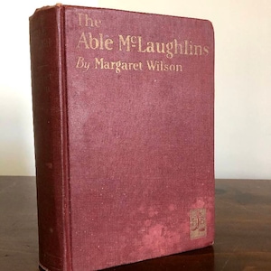 May include: A burgundy hardback book with gold lettering on the spine and front cover. The title is "The Able McLaughlins" by Margaret Wilson.