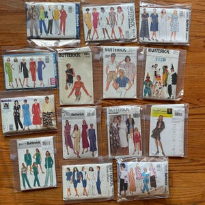 May include: A collection of vintage Butterick sewing patterns in plastic sleeves. The patterns feature illustrations of various clothing designs, including dresses, jackets, and pantsuits. The patterns are in various sizes and styles, with some labeled "Classics Fast & Easy."