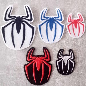 Könnte beinhalten: Fünf gestickte Bügelbilder mit einem stilisierten Spinnenmotiv. Die Patches sind in verschiedenen Farben, darunter Schwarz, Weiß, Rot und Blau.