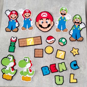 Könnte beinhalten: Ein Set Bügelbilder mit Figuren aus der Super Mario Bros. Videospielserie. Die Bügelbilder zeigen Mario, Luigi, Toad und einen Fragezeichenblock. Die Bügelbilder sind perfekt, um Kleidung, Taschen oder anderen Accessoires einen lustigen Touch zu verleihen.