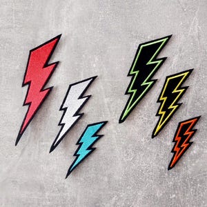 Könnte beinhalten: Sechs Bügelbilder in Form von Blitzen. Die Patches sind in verschiedenen Farben, darunter Rot, Weiß, Blau, Grün, Gelb und Orange.