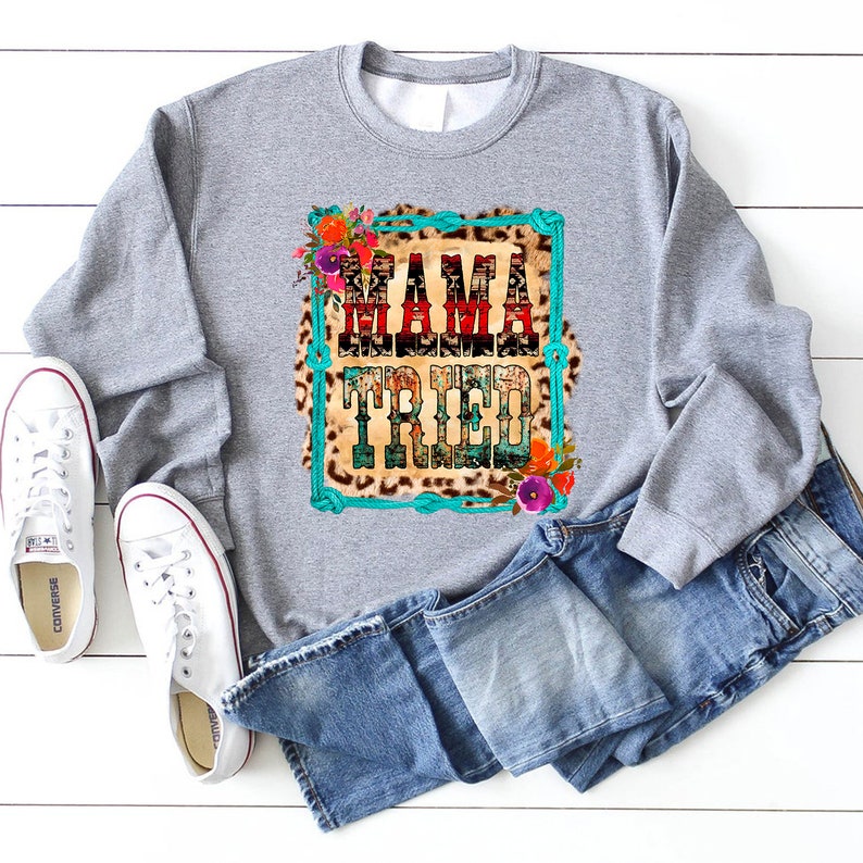 Puede incluir: Sudadera gris con un estampado gr&aacute;fico de un fondo de estampado de leopardo con ribete de cuerda turquesa y el texto "Mama Tried" en rojo, blanco y azul. El gr&aacute;fico est&aacute; rodeado de flores.