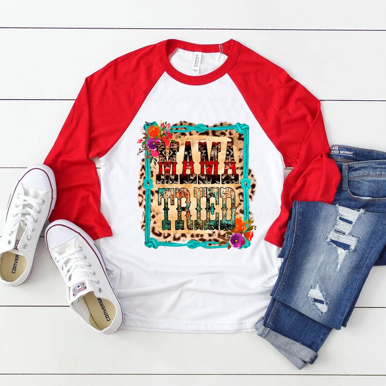 Puede incluir: Camiseta de b&eacute;isbol blanca y roja con un dise&ntilde;o de estampado de leopardo y el texto "Mama Tried" en azul turquesa. La camiseta est&aacute; rodeada de acentos florales.