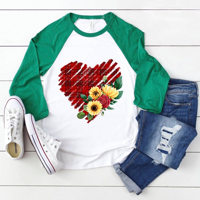 May include: A white and green baseball tee shirt with a red plaid heart design and a floral arrangement of sunflowers and roses.