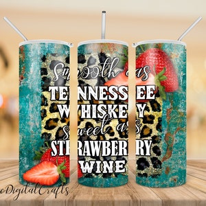 May include: A stainless steel tumbler with a turquoise and gold background featuring a leopard print and strawberries. The tumbler has the text "Smooth as Tennessee Whiskey Sweet as Strawberry Wine" printed on it.