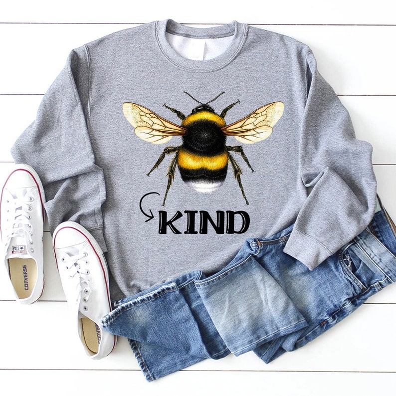 May include: Gray sweatshirt with a black and yellow bumblebee graphic and the word "KIND" in black text.