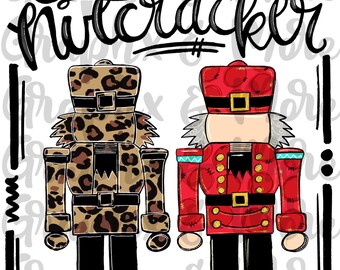 Op de afbeelding: Sublimatiedesign "Zoontje van een notenkraker" met twee notenkrakerfiguren. Een notenkraker draagt een rood-gouden uniform, terwijl de andere een outfit met luipaardprint draagt. De tekst "Zoontje van een notenkraker" is in zwarte cursieve letters boven de figuren geschreven.