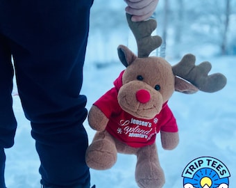 May include: A child holds a plush reindeer wearing a red hooded sweatshirt with the text "Jensen's Lapland adventure".