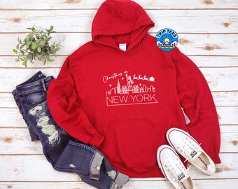 May include: Red hooded sweatshirt with a white graphic of the New York City skyline and the text "Christmas in New York".