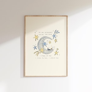 May include: A framed art print featuring a whimsical illustration. The artwork depicts a crescent moon with an astronaut inside, surrounded by stars. Text includes "I'm an astronaut, you're the moon." and "I stare at you, I sing to you, I circle you."