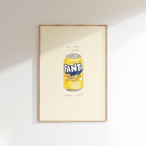 Könnte beinhalten: Ein gerahmter Druck mit einer Aquarellillustration einer gelben Fanta-Zitronen-Limonaden-Dose. Die Dose hat das Fanta-Logo in Blau und eine Zitronenscheiben-Grafik. Der Text oben lautet "Hot Girls Drink" und unten "Lemon Fanta."