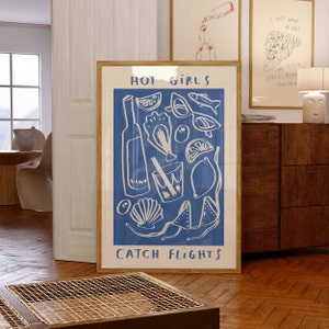 May include: A blue poster with white illustrations of a bottle of wine, a glass of wine, lemons, seashells, and sunglasses. The text "HOT GIRLS CATCH FLIGHTS" is printed on the poster.