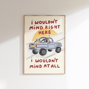 May include: A framed art print featuring a light blue pickup truck with two people and a dog inside. The artwork includes the text "I wouldn't mind right here" and "I wouldn't mind at all" in maroon.