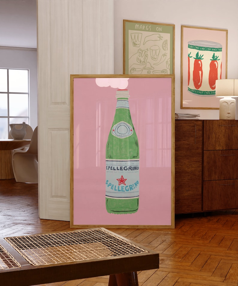 May include: A pink framed poster with a white cloud above a green glass bottle of sparkling water with a red star and the text "SPELLEGRINO" on the label.