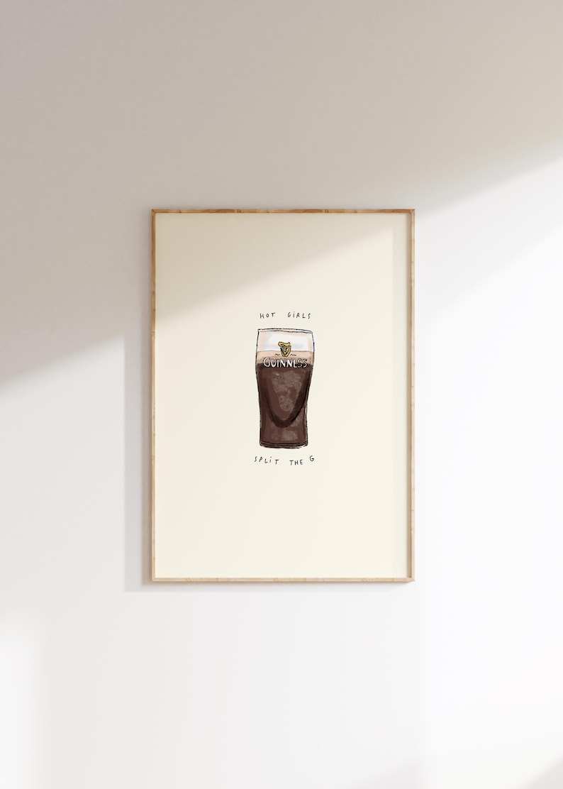 K&ouml;nnte beinhalten: Gerahmter Kunstdruck mit einem Pint Guinness. Das Kunstwerk enth&auml;lt das Guinness-Logo und den Text "Hot Girls Split the G". Der Druck hat einen minimalistischen Stil mit cremefarbenem Hintergrund und Holzrahmen.