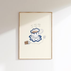 Op de afbeelding: Een ingelijste kunstprint met een illustratie van een theekopje met een blauw-wit bloemmotief, een theezakje en de tekst "Hot girls drink too much tea."