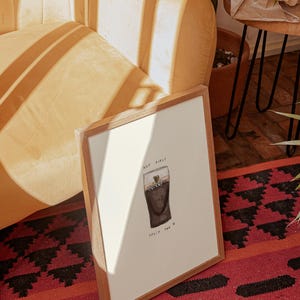 K&ouml;nnte beinhalten: Ein gerahmter Druck mit einer Aquarellillustration eines Guinness-Pints. Das Kunstwerk enth&auml;lt das Guinness-Logo und den Text "NOT GUILTY, SPLIT THE G". Der Rahmen besteht aus hellbraunem Holz.