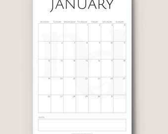 May include: A white spiral-bound calendar open to January. The word "JANUARY" is at the top. The days of the week are listed across the top, with dates in the grid below. A notes section is at the bottom.