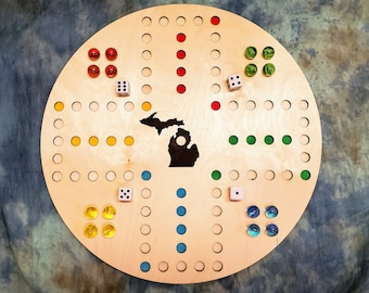 May include: A wooden game board featuring a silhouette of the state of Michigan in the centre. The board is circular and divided into sections with different coloured dots. There are also dice and marbles on the board.