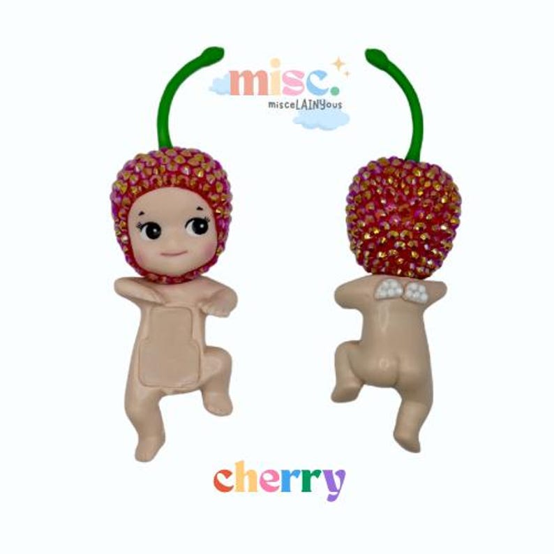 Puede incluir: Dos figuras con forma de beb&eacute;s con cabezas en forma de cereza. Las cabezas de cereza son rojas con detalles brillantes y tallos verdes. La palabra "cherry" est&aacute; escrita en colores del arco&iacute;ris en la parte inferior de la imagen.