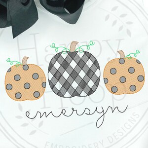 May include: A white onesie with a black and white checkered pumpkin, two orange pumpkins with black polka dots, and the name "emersyn" embroidered on the front.