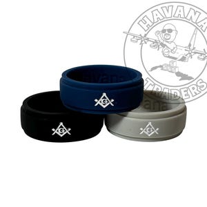May include: Three silicone rings with a white square and compass design. The rings are black, blue, and gray.