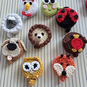 May include: A collection of handmade crochet animal ornaments, including a chicken, frog, ladybug, sheep, dog, lion, owl, fox, and bird. Each ornament features detailed stitching and vibrant colors, perfect for children's decor or craft projects.