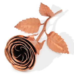 May include: A handcrafted copper rose sculpture with detailed petals and leaves. The rose is a warm copper color, with a stem and leaves extending from the flower. The sculpture is a decorative piece, perfect for home decor.