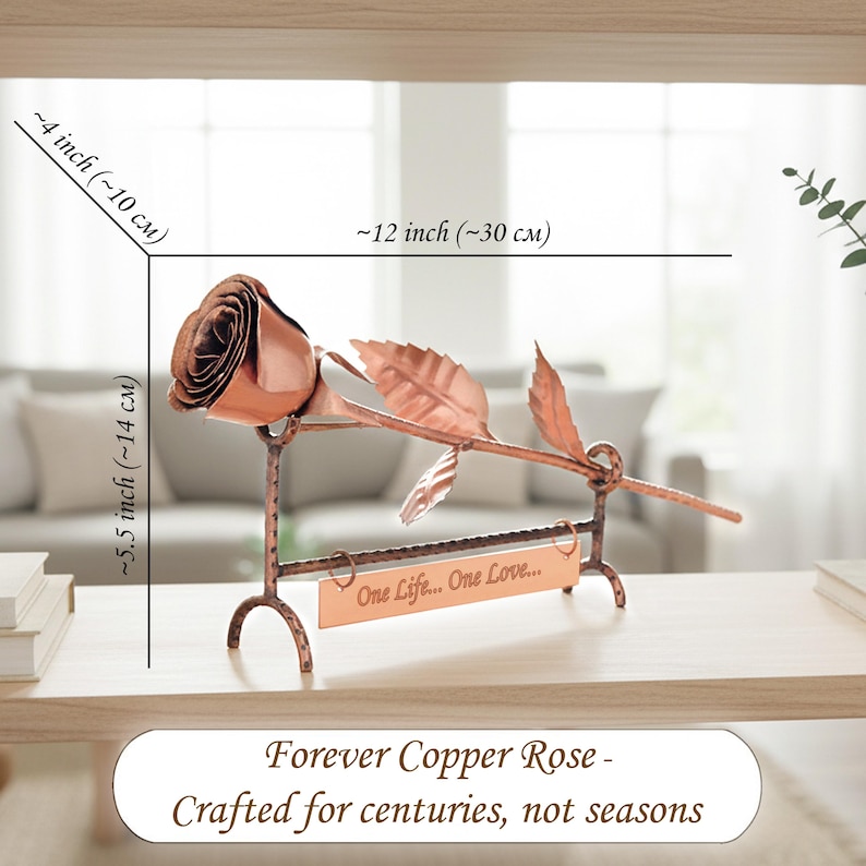 May include: A copper rose sculpture resting on a hammered metal stand with a rectangular plaque engraved with the text One Life... One Love... The sculpture measures approximately 30 cm in length, 10 cm in width, and 14 cm in height.