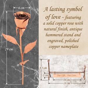 May include: A solid copper rose with a natural finish, measuring 29 cm in height and 6 cm in width. It includes an antique hammered stand and a polished copper nameplate measuring 14 cm by 2 cm, engraved with the text One Life... One Love...