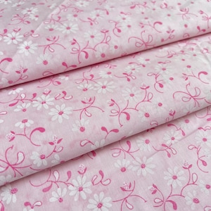 May include: Pink fabric with a white floral pattern. The fabric is folded in thirds, showing the pattern on all three layers.