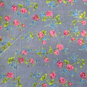 May include: A blue fabric with a repeating pattern of pink roses and blue flowers. The fabric has a subtle texture.