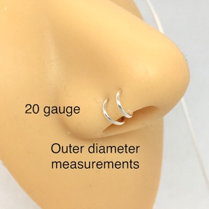 May include: Two silver nose rings, one slightly larger than the other, are shown on a model. The rings are 20 gauge and the text "Outer diameter measurements" is also visible.