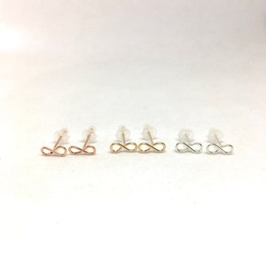 May include: Three pairs of infinity symbol earrings in gold, rose gold, and silver.