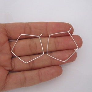 May include: A pair of silver geometric hoop earrings. The earrings are shaped like a pentagon and are about 1 inch in diameter.