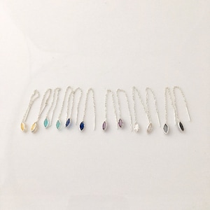 Puede incluir: Un conjunto de 10 pendientes de cadena de plata con acentos de piedras preciosas de diferentes colores. Las piedras preciosas tienen forma de marquesa e incluyen amarillo, azul, azul verdoso, morado y transparente.