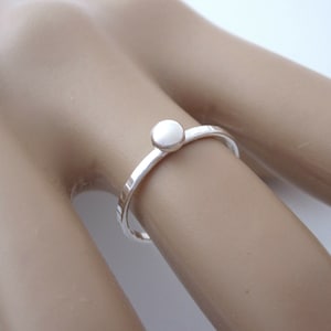 May include: A simple silver ring with a small, round, silver bead on top.