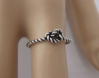 May include: A silver ring with a knotted rope design.