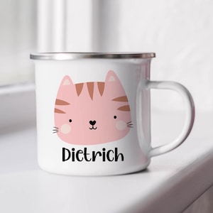 May include: White enamel mug with a pink cat face and brown stripes. The mug has a silver rim and handle. The name "Dietrich" is printed below the cat.