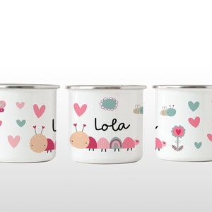 May include: Three white enamel mugs with a pink and green ladybug design. The middle mug has the name "Lola" written on it.