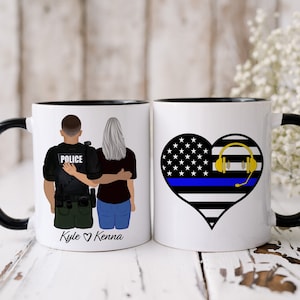 May include: Two white coffee mugs with black handles and black rims. One mug features a cartoon illustration of a police officer and a woman with the text "Kyle ♥ Kenna". The other mug features a heart-shaped American flag with a blue line and a gold headset.
