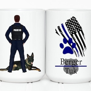 Könnte beinhalten: Weiße Keramik-Kaffeetasse mit einer blau-schwarzen amerikanischen Flagge mit einem blauen Pfotenabdruck und dem Text "Berger Tuk" auf der einen Seite. Die andere Seite zeigt einen Polizisten mit einem Deutschen Schäferhund.